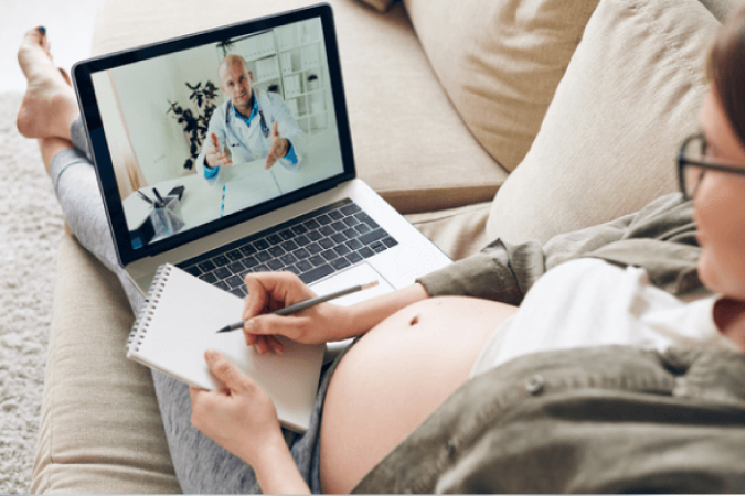 Laptop auf den Beinen einer Schwangeren, die sich Notizen macht